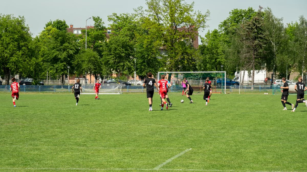 Amateur soccer players compete in a local match at a grassy field in Wrocław, Poland.