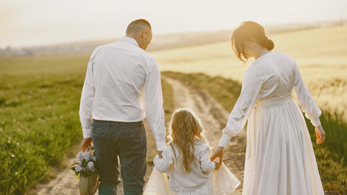 A family of three walks down a rural path during sunset, symbolizing togetherness and love.